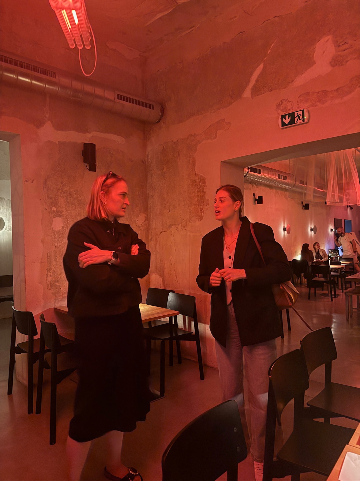 Two members talking over drinks in a warm-lit Prague bar